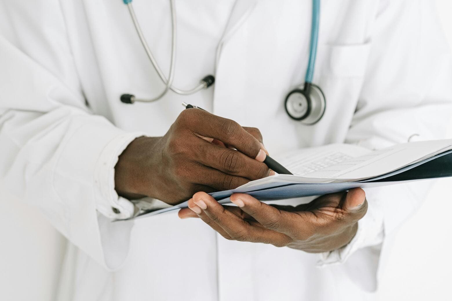 Médico segurando prontuário e preenchendo informações em artigo sobre saúde internacional preço.