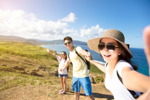 Familia con seguro de viaje familiar tomándose una selfie mientras hacen trekking en una montaña.