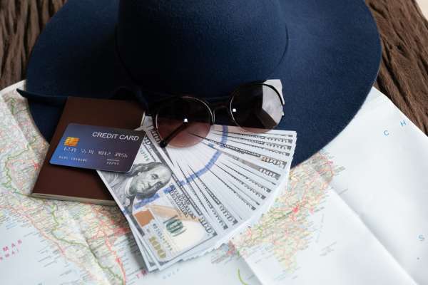 imagem de chapéu, óculos escuros, cartão de crédito, dinheiro e mapa na mesa para ilustrar o tema “quanto custa uma viagem para a itália
