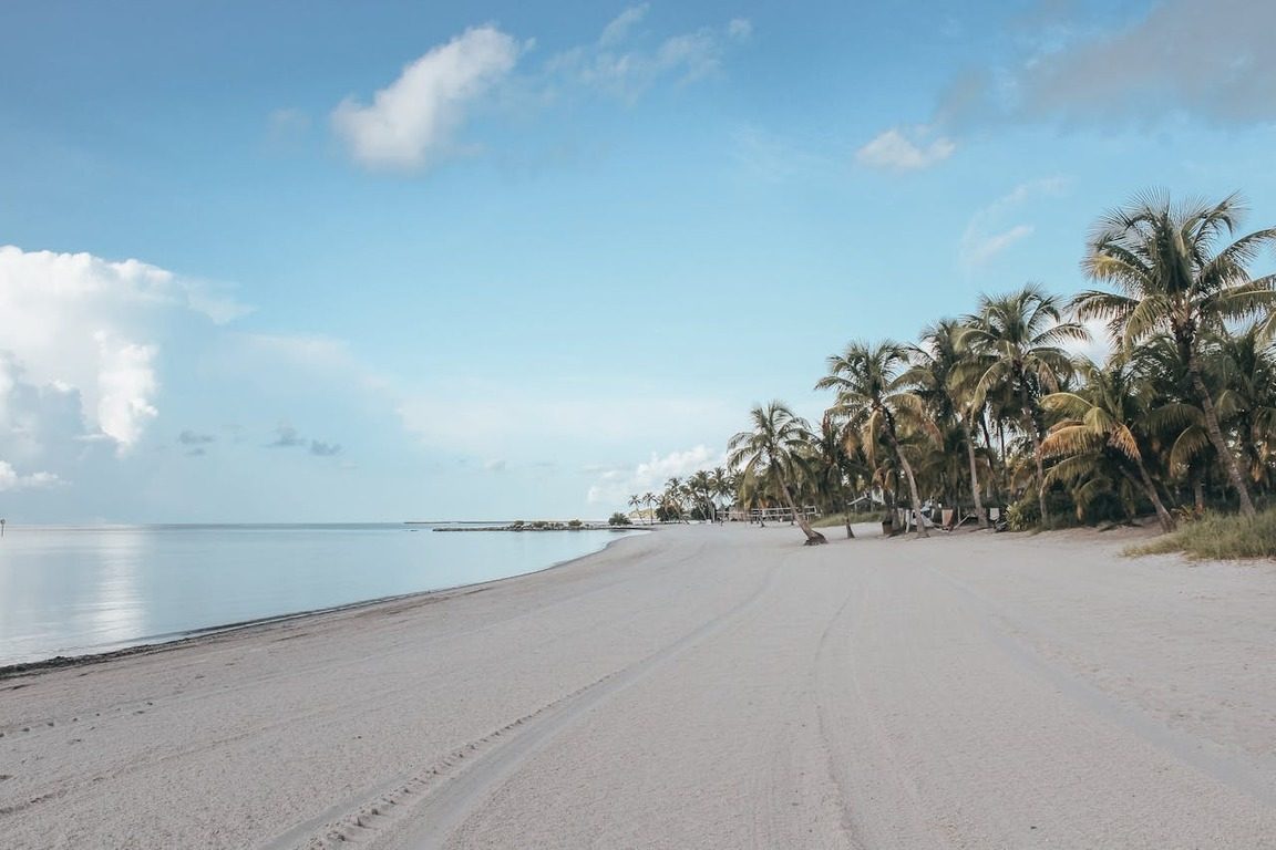 Foto de uma praia de areia branca com coqueiros e mar em Key West, ilustrando artigo sobre o que fazer na Flórida com tranquilidade.