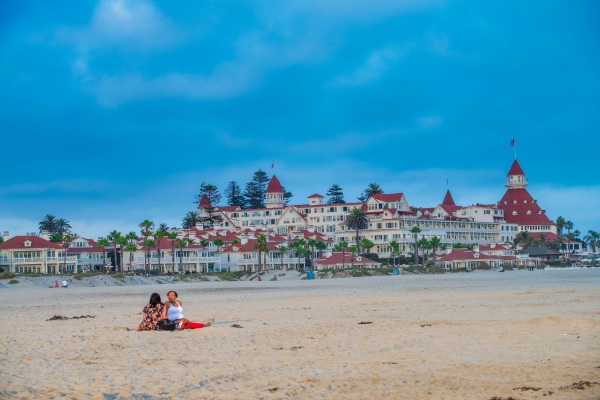 Personas disfrutando de Coronado Beach, con el Hotel del Coronado en el fondo, una de las cosas que hacer en San Diego.