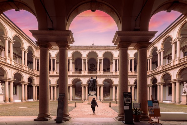 Turista caminando al atardecer por el patio interior de la Pinacoteca di Brera, Milán, Italia