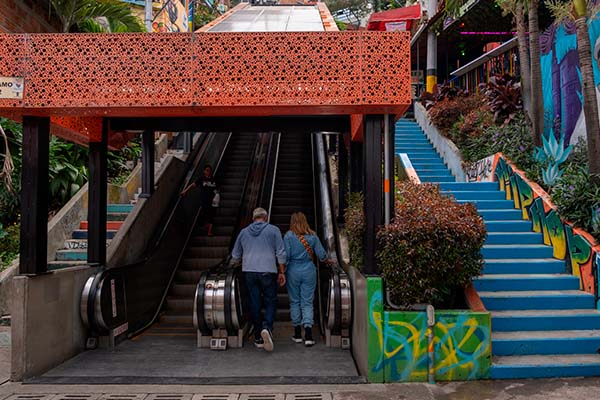 Turistas en una escalera mecánica al aire libre en el famoso barrio de la Comuna 13, Medellín, Colombia
