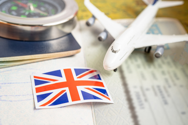 Avión de juguete, documentos y bandera británica sobre una mesa, representando un viaje al Reino Unido.