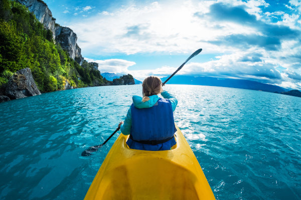 Mujer turista haciendo kayak en un lago azul de la Patagonia chilena