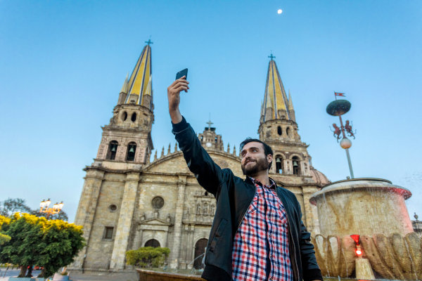 Hombre turista joven tomándose una selfie con su teléfono móvil en la Catedral de la ciudad de Guadalajara, Jalisco, México.