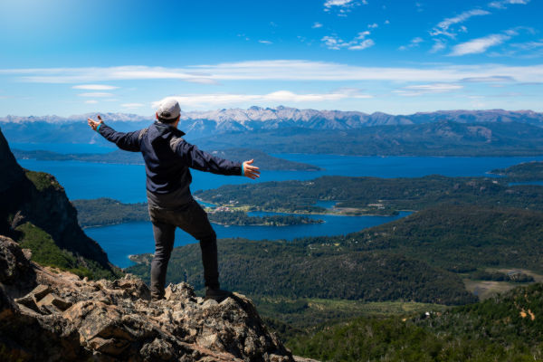 Turista mexicano usando su celular mientras recorre los parques de Buenos Aires, con la escultura Floralis Genérica al fondo.