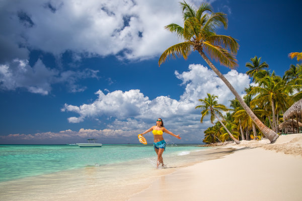 Mujer turista feliz en una playa de Punta Cana en un día soleado con palmeras de fondo