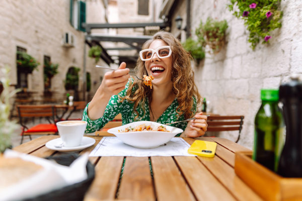 Mujer joven comiendo pasta italiana en un restaurante en la calle en Roma. Concepto de gastronomía italiana y viajes.