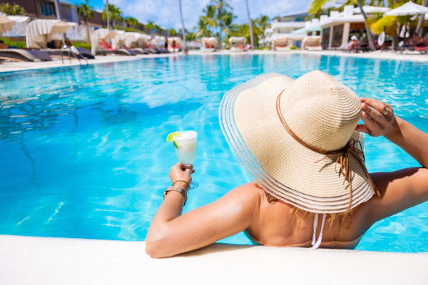 Mujer turista con sombrero disfrutando de un cóctel en una piscina en un hotel del Caribe