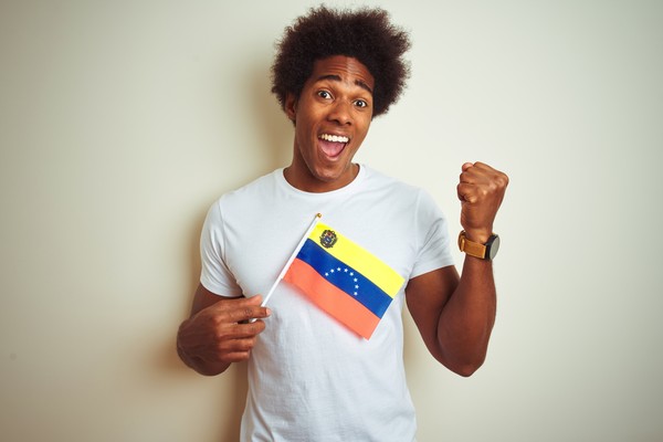 Hombre con la bandera venezolana de pie sobre un aislado fondo blanco.