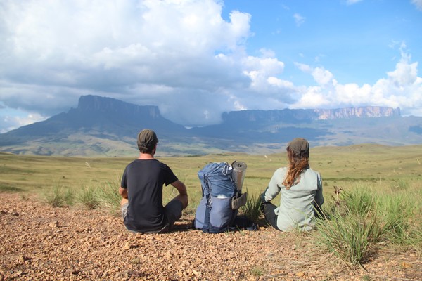Pareja sentada en el suelo con mochila en medio en el camino hacia el Monte Roraima, Venezuela.