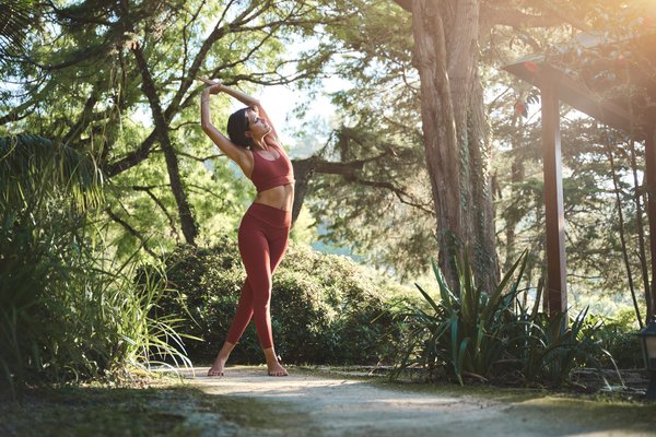Mujer esbelta con ropa deportiva descalza en el sendero de un bosque.