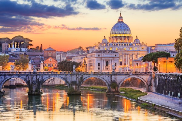 Ciudad de Roma con la Basílica de San Pedro en el centro, a orillas del río Tíber, al atardecer.