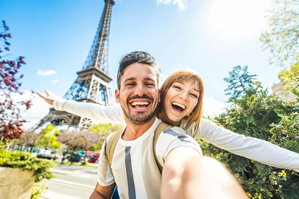 Pareja feliz tomándose una selfie frente a la Torre Eiffel