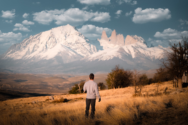 Hombre parado en un campo del Parque Nacional Torres del Paine, con vistas a las montañas en otoño