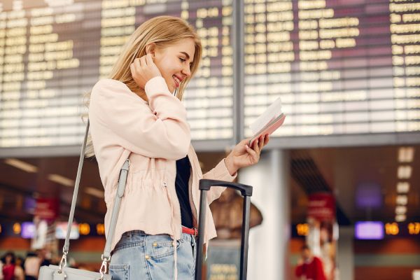 imagem de viajante de costas, em aeroporto, com uma câmera fotográfica no ombro direito