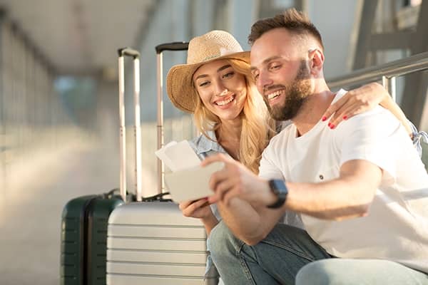 Casal tirando fotos com suas malas antes de embarcar para Porto Seguro.