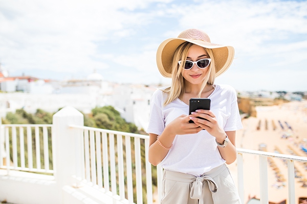 mulher de chapéu e óculos escuros utilizando celular