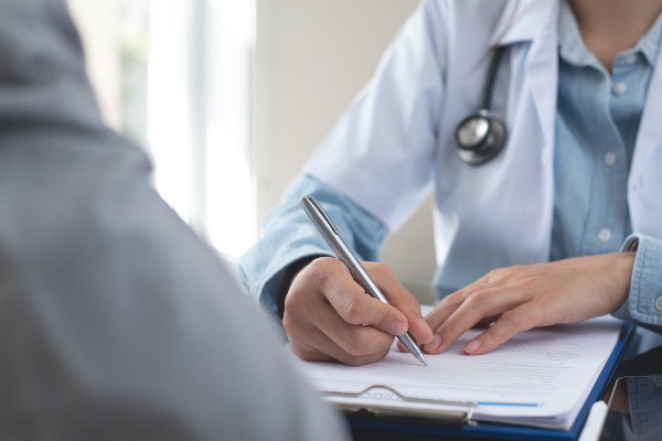Médico escribiendo una receta para un paciente en el contexto de una consulta médica