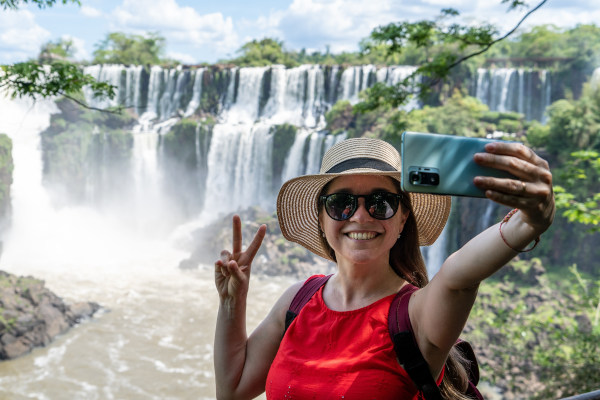 Turista femenina tomándose una selfie frente a las Cataratas del Iguazú, Misiones, Argentina, en un día soleado