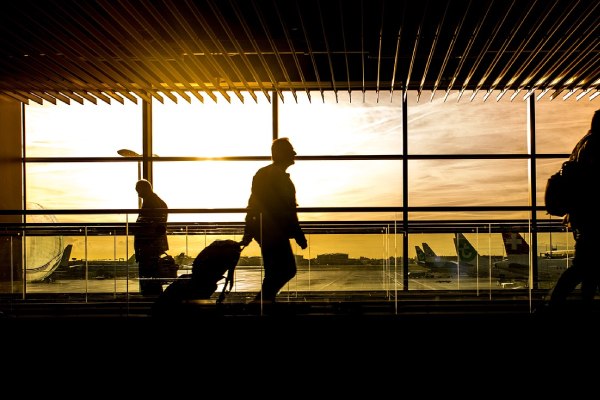 imagem de pessoas transitando a pé em um aeroporto durante o por do sol para falar sobre seguro viagem Orlando                         