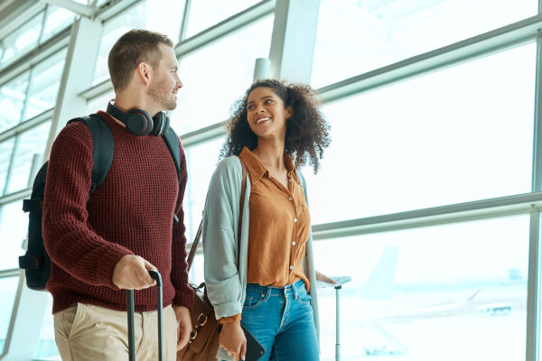 Pareja sonriendo con maletas en una terminal de aeropuerto