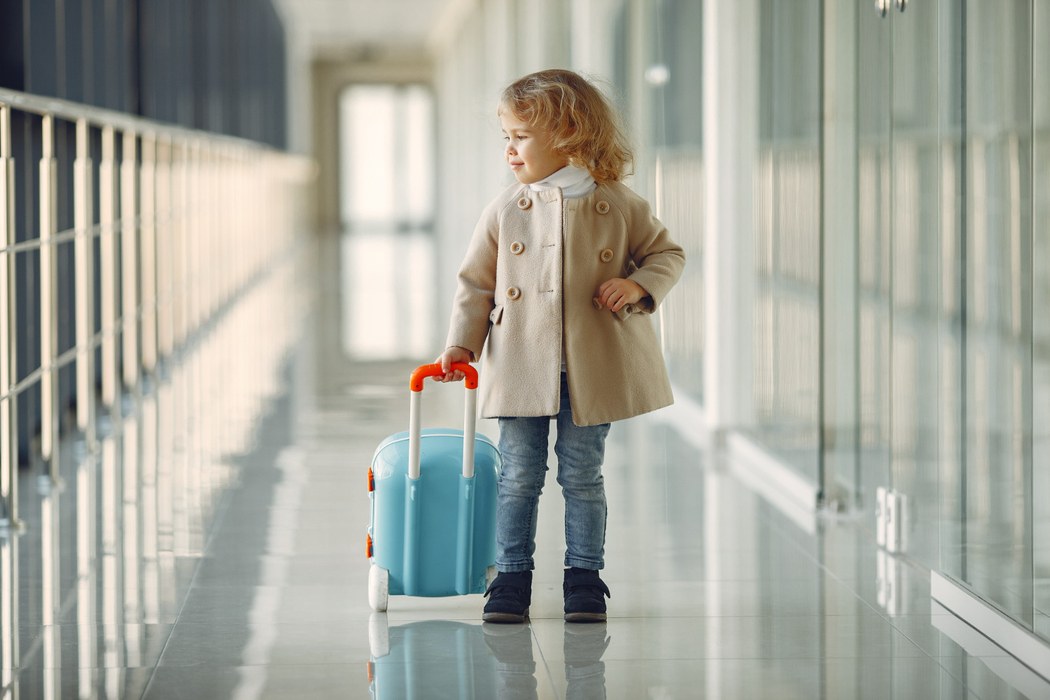 Menina com mala no aeroporto prestes a embarcar, ilustrando artigo sobre quantos anos pode viajar sozinho de avião.