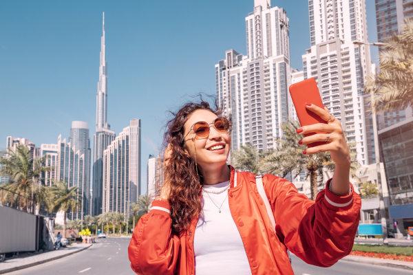 Chica tomándose una selfie con el Burj Khalifa y los edificios de Dubai de fondo.