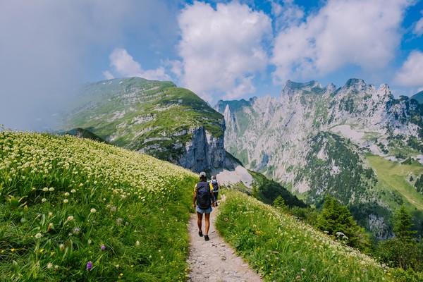 Personas con mochilas sobre una montaña haciendo senderismo hacia la cresta de montaña Saxer Lucke en Alpstein, Suiza.