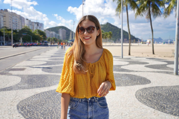 Mujer sonriente caminando por la costanera de Copacabana en Río de Janeiro.