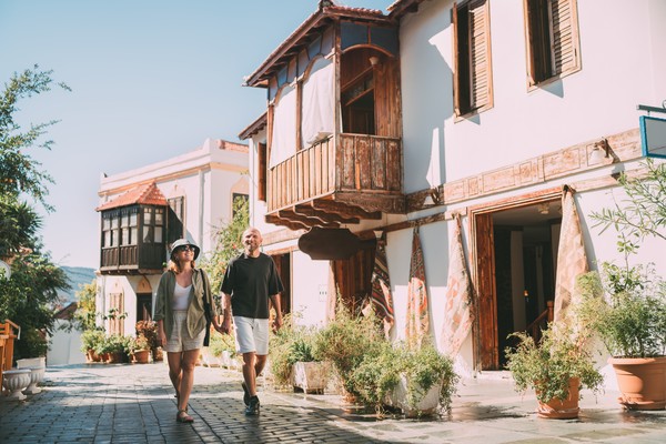 Pareja de mediana edad caminando de la mano a lo largo de una estrecha calle en el centro histórico de la ciudad de Kas, Turquía.
