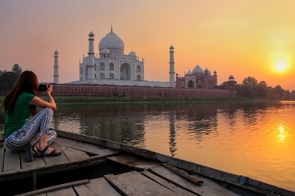 Mujer tomando una foto del Taj Mahal, India, a orillas del río Tíber al atardecer.