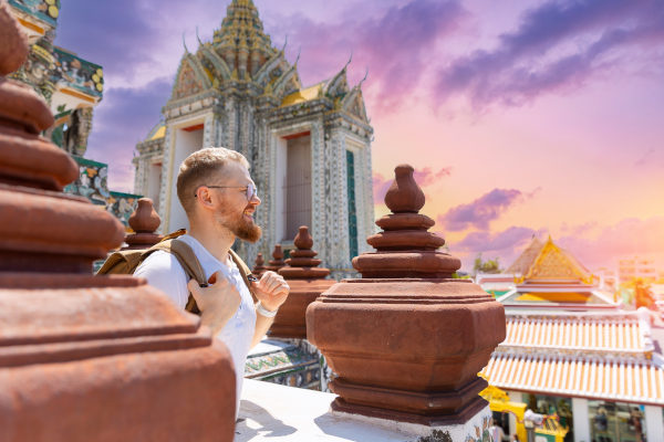 Turista caucásico recorriendo Bangkok al atardecer con una sonrisa