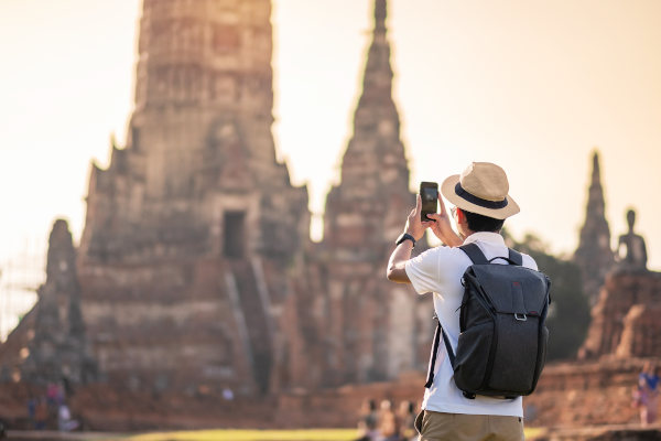 Viajero con sombrero y mochila fotografiando con smartphone el templo de Wat Chaiwatthanaram, Parque Histórico Ayutthaya, Tailandia.