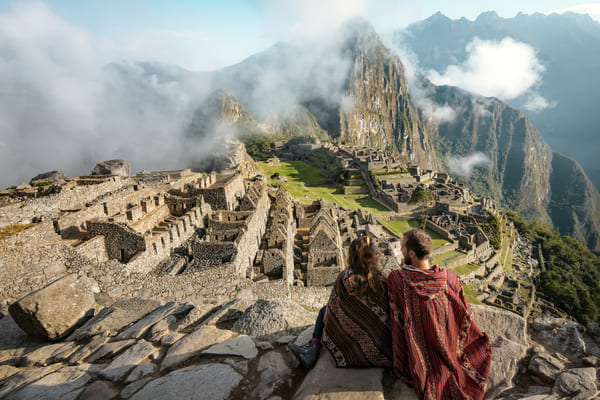 Pareja vestida de ponchos observando las ruinas de Machu Picchu