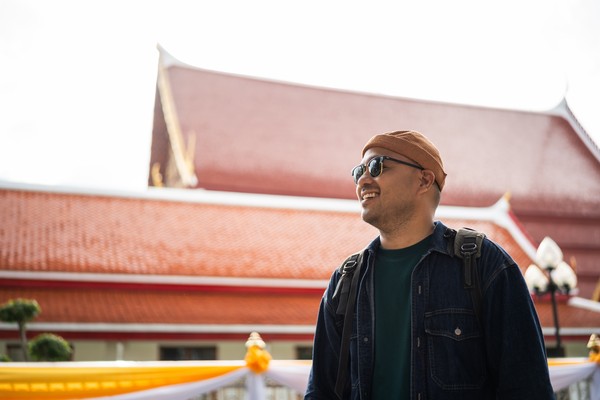 Hombre turista feliz con un templo de Bangkok de fondo en Tailandia.