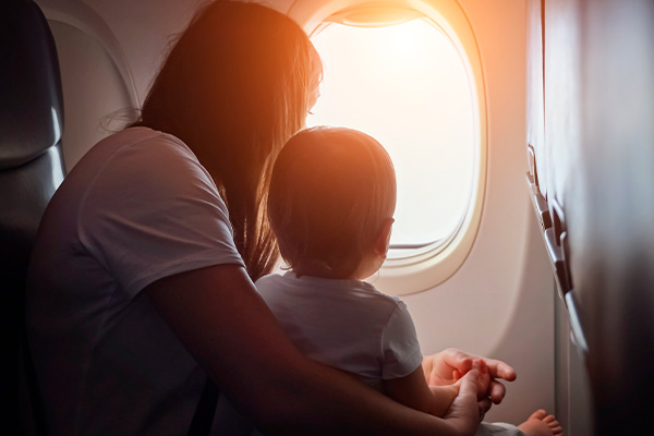 Madre con bebé en el regazo mirando por la ventanilla de un avión