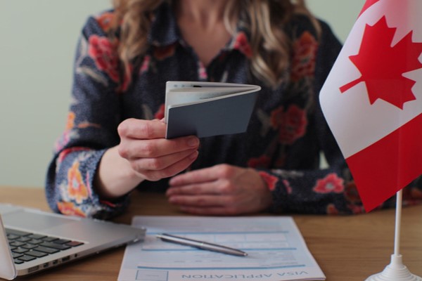 Mujer con pasaporte en mano y bandera de Canadá