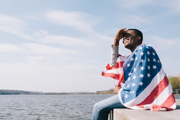 imagem de homem enrolado em uma bandeira dos eua para representar viagem para os estados unidos