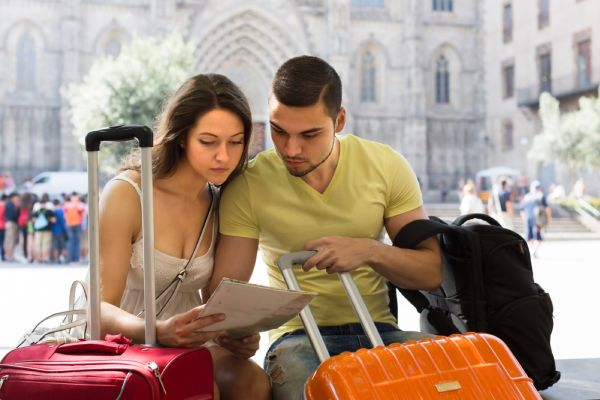 imagem de casal analisando um mapa e segurando malas de viagem e mochilas em viagem para a Itália