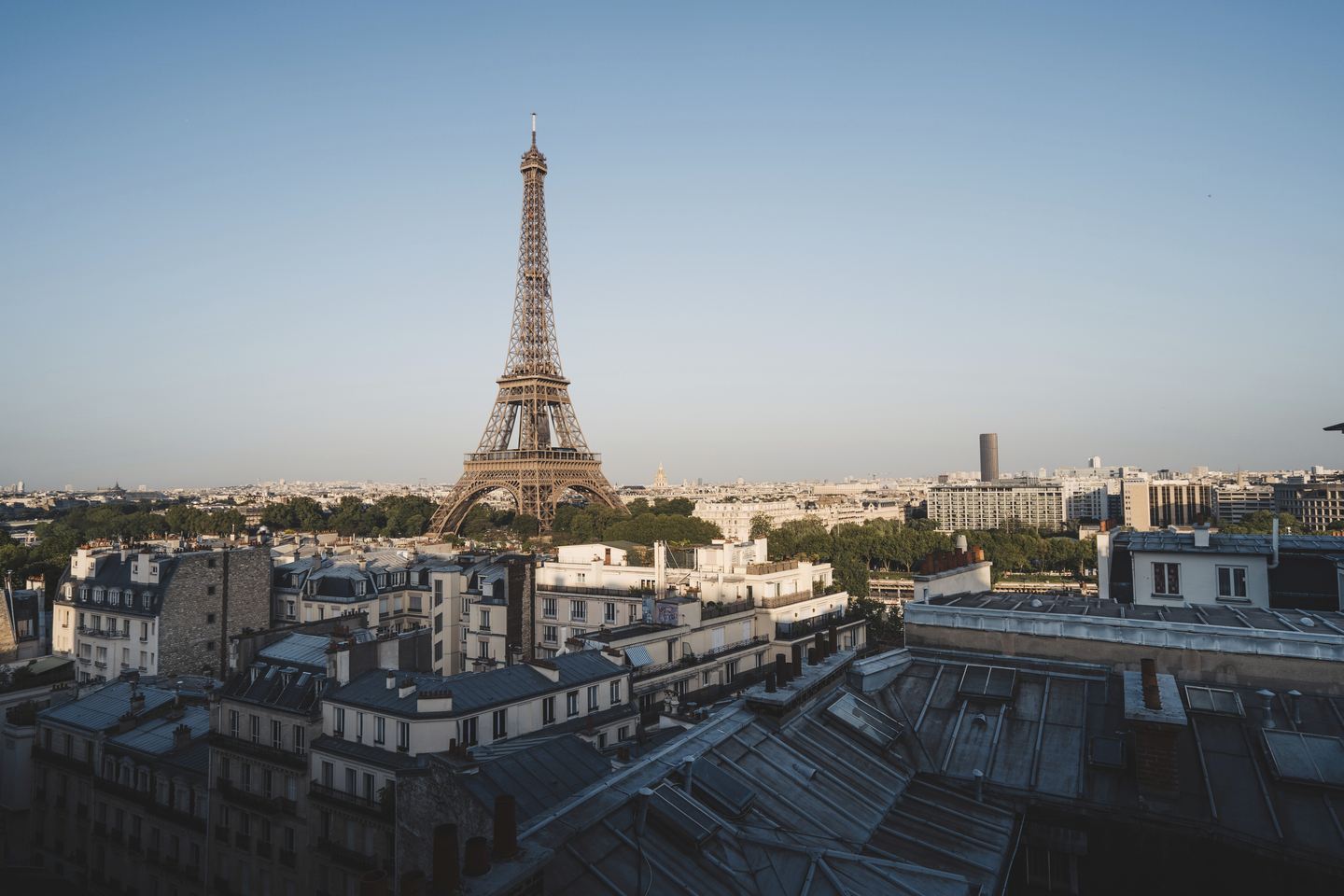 Imagem de três mulheres caminhando e rindo com a Torre Eiffel ao fundo para ilustrar artigo sobre quanto custa uma viagem para Paris