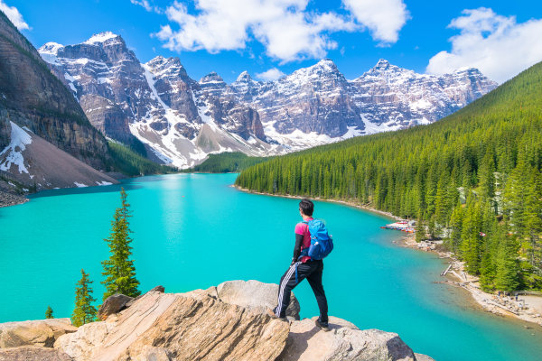Hombre parado en una roca con vistas al Lago Moraine, Parque Nacional de Banff, Canadá