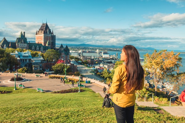 Mujer turista observando el río San Lorenzo y el castillo de Chateau Frontenac desde un parque en Québec, Canadá