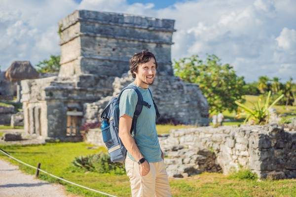 Hombre turista con mochila recorriendo las ruinas de Tulum, Riviera Maya, México.
