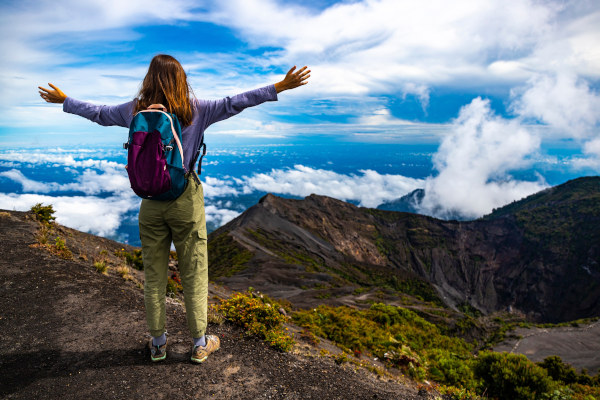 Chica con mochila se sienta en la cima del volcán Irazú en Costa Rica, paisaje volcánico del Parque Nacional del Volcán Irazú.