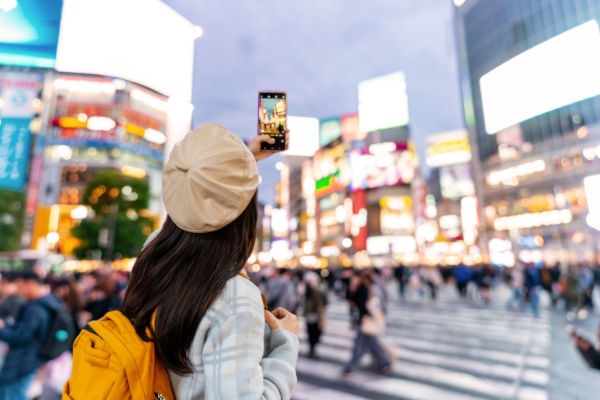 Turista tomando una foto en el cruce de Shibuya, uno de los lugares más icónicos de Tokio, Japón.