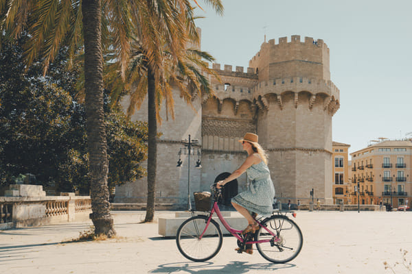 Mujer montando bicicleta por torres de Serranos puerta de la ciudad de Valencia España