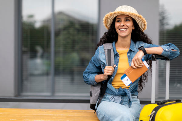 Mujer joven feliz viajando sola, con su pasaporte y boletos de avión en la mano.