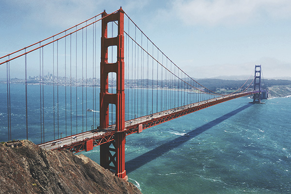Vista da Ponte Golden Gate, com mar azulado e céu com nuvens.                     